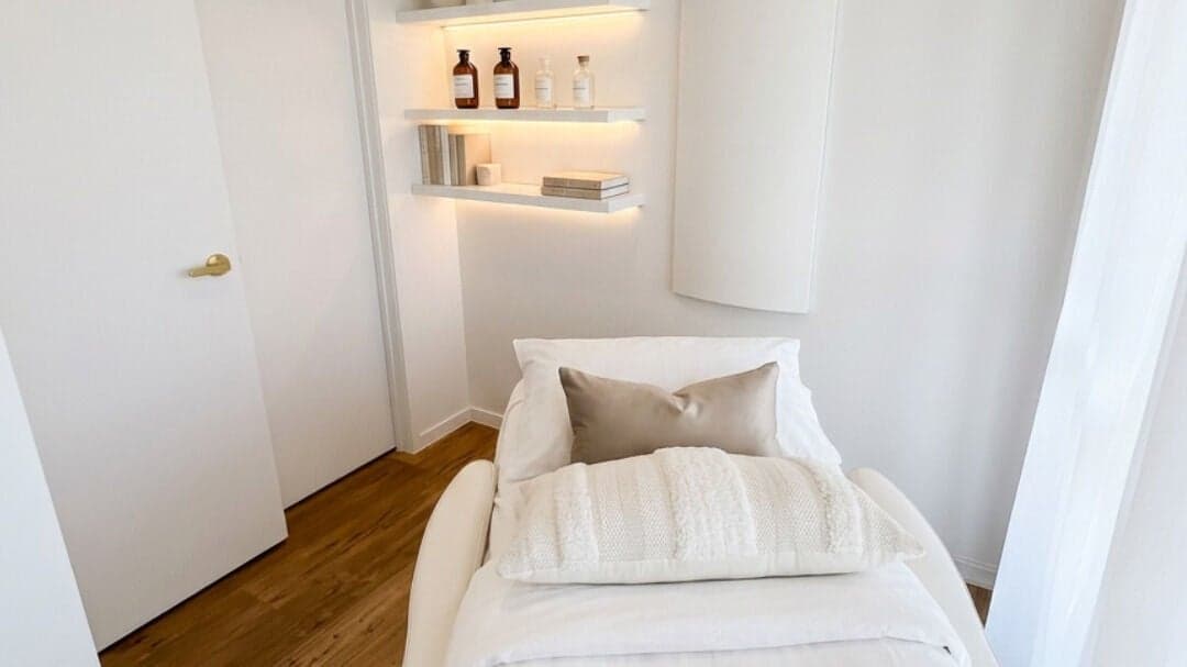 Treatment room at e-skin with plush bedding and shelving